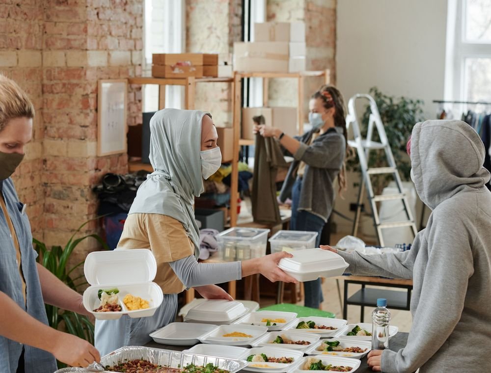 Volunteers handing packed meals to a person at a community support centre