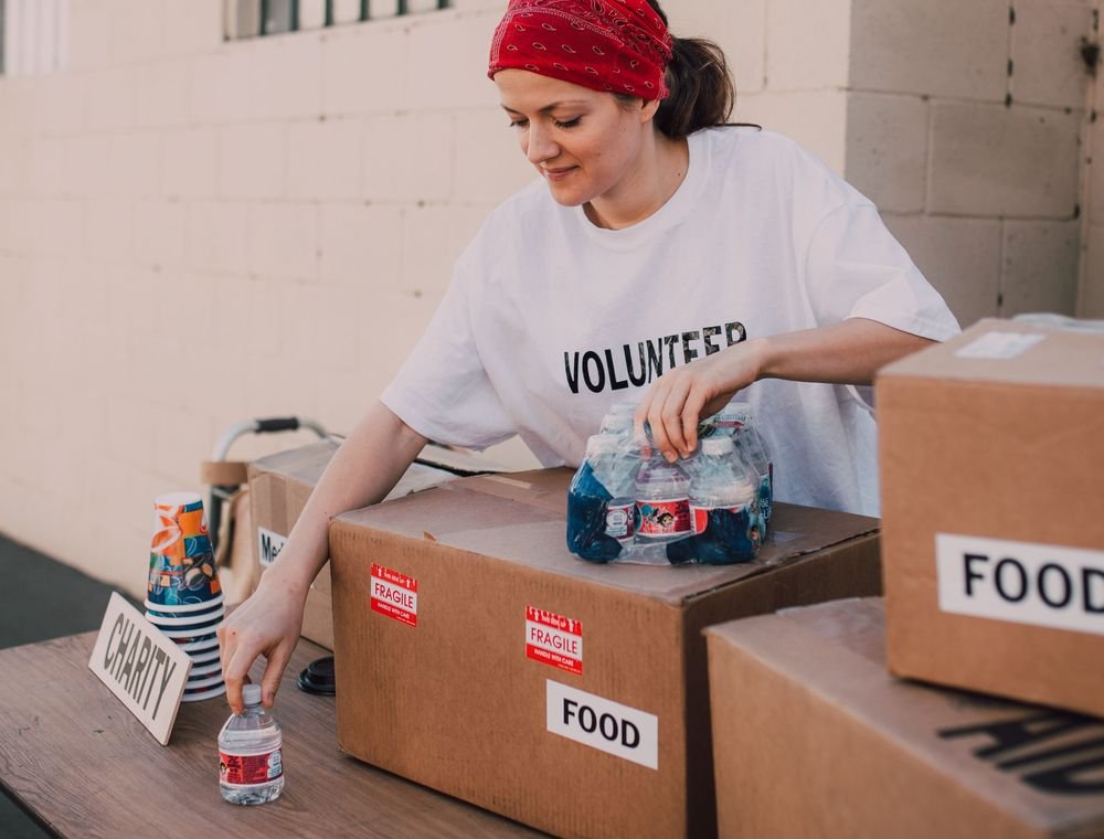 Volunteer preparing labelled food donation boxes and drinking water