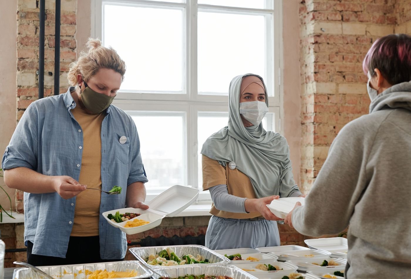 Volunteers handing prepared meal boxes to a community member