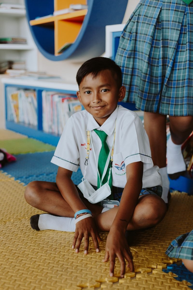 Smiling schoolboy sitting in a colourful classroom